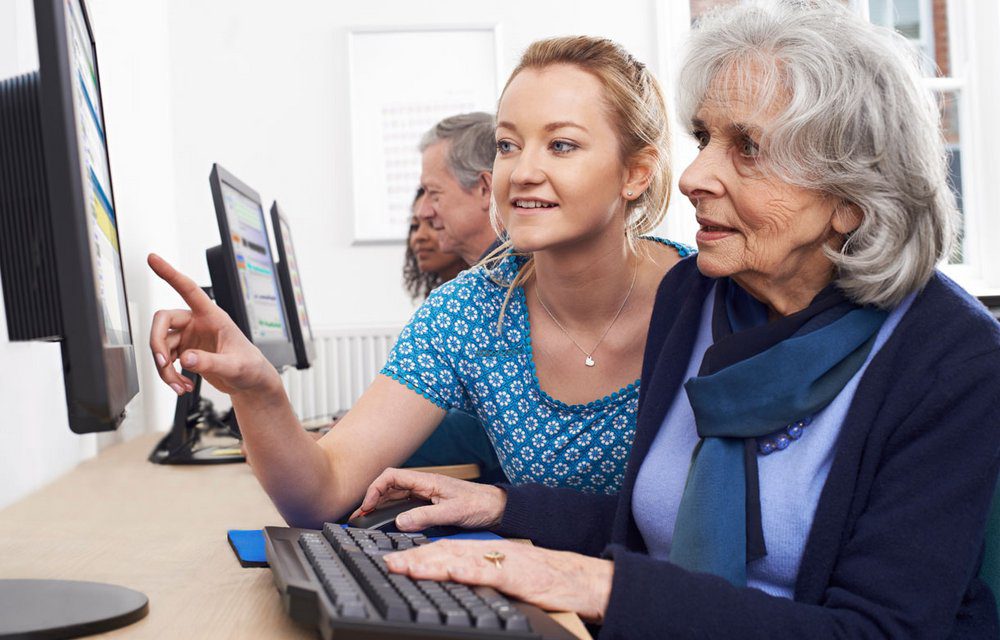 Photo d'une jeune femme aidant une femme mature à se servir d'un ordinateur